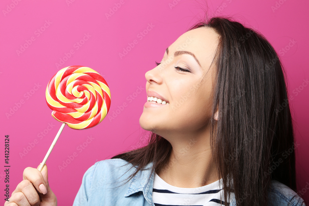 Young woman with lollipop on pink background