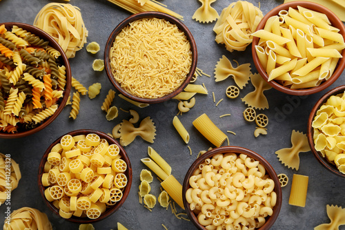 Different kinds of pasta in bowls on grey table photo