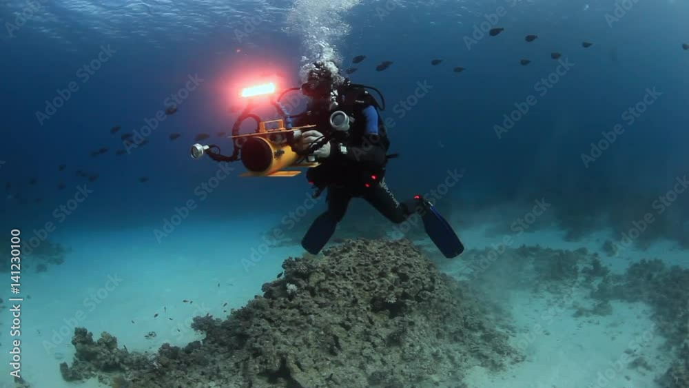 Egypt - 01 March 2012: Cameraman diver swimming deep underwater in Red sea. World of colorful beautiful wildlife of reefs and algae. Abyssal diving. Egypt - 01 March 2012: Cameraman diver swimming deep underwater in Red sea. World of colorful beautiful wildlife of reefs and algae. Abyssal diving.