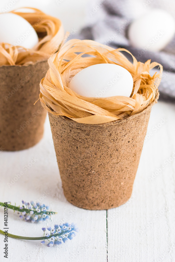 easter eggs in nests on white wooden table
