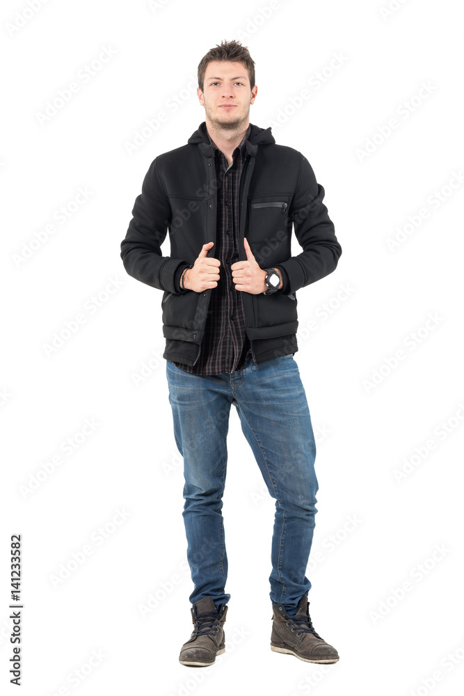Confident young casual male in hooded black winter jacket and jeans. Full body length portrait over white studio background. Confident young casual male in hooded black winter jacket and jeans. Full body length portrait over white studio background.