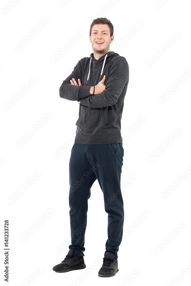 Happy laughing young sportive athlete in sweatshirt and sweatpants with crossed arms. Full body length portrait over white studio background. Happy laughing young sportive athlete in sweatshirt and sweatpants with crossed arms. Full body length portrait over white studio background.