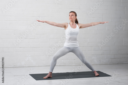 Beautiful young woman doing Yoga Warrior Pose