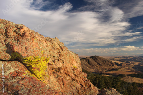 Bright green lichen grows on a red granite rock face overlooking the foothills of Colorado's front range.