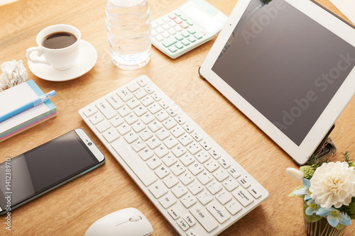 smartphone with pencil,coffee cup,calendar,calculator,bottle water,computer pc,tablet and flower on wood office table desk.