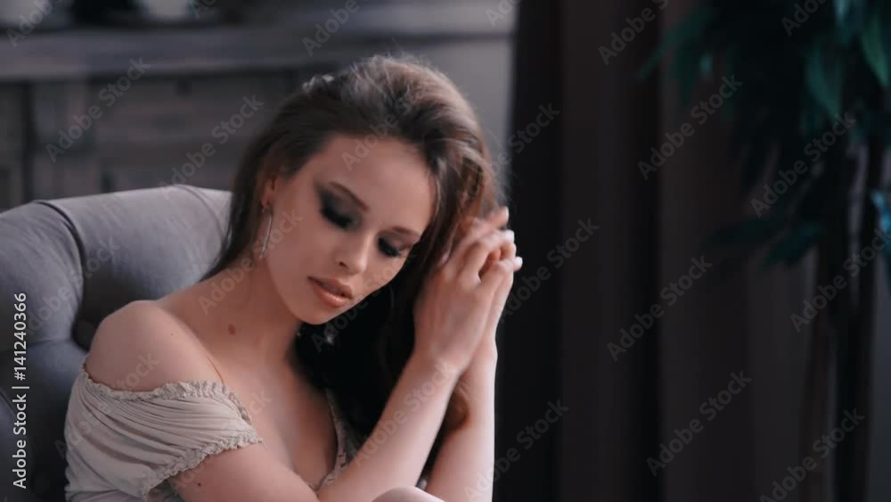 A brunette girl sitting in the interior poses sexually on the camera A brunette girl sitting in the interior poses sexually on the camera