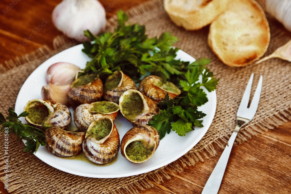 Escargots de Bourgogne - Snails with herbs butter, gourmet dish in French traditional  with parsley and bread on white platter