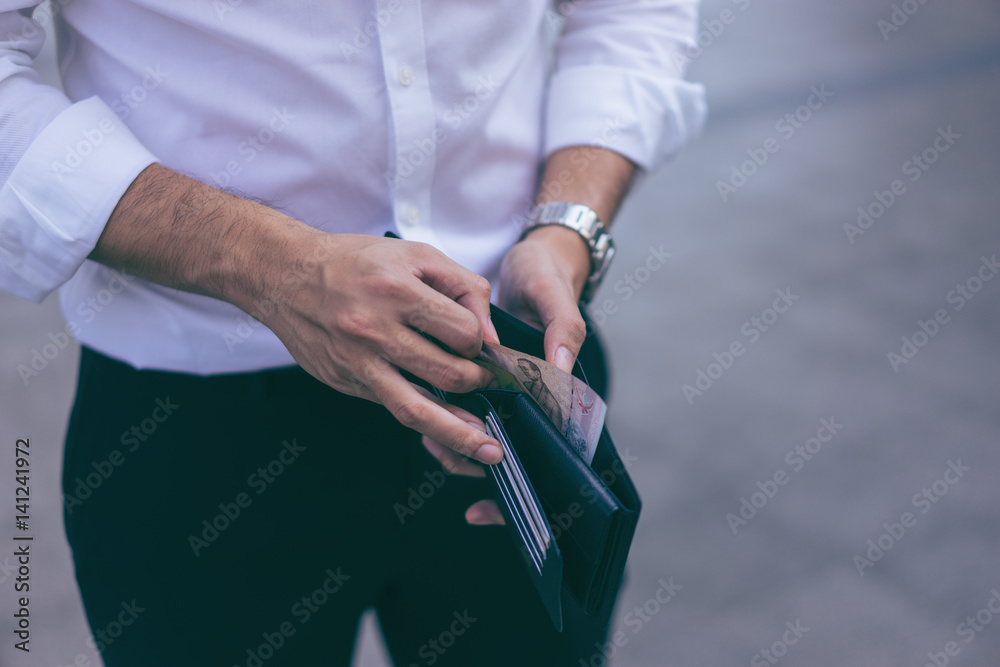 Fototapeta premium Man standing holding black wallet and picking up a money