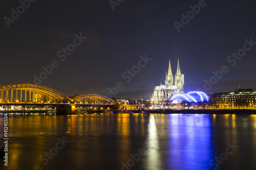 Cologne Cathedral (German: Kolner Dom, officially Hohe Domkirche St. Peter und Maria) and Hohenzollern Bridge across the Rhine, Germany, at dusk