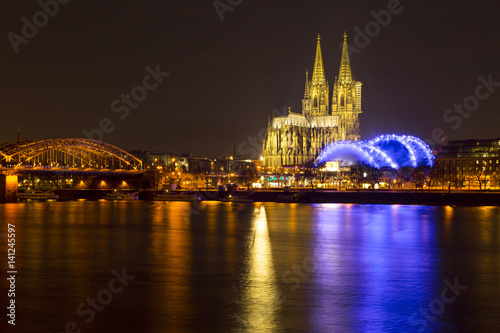 Cologne Cathedral  German  Kolner Dom  officially Hohe Domkirche St. Peter und Maria  and Hohenzollern Bridge across the Rhine  Germany  at dusk