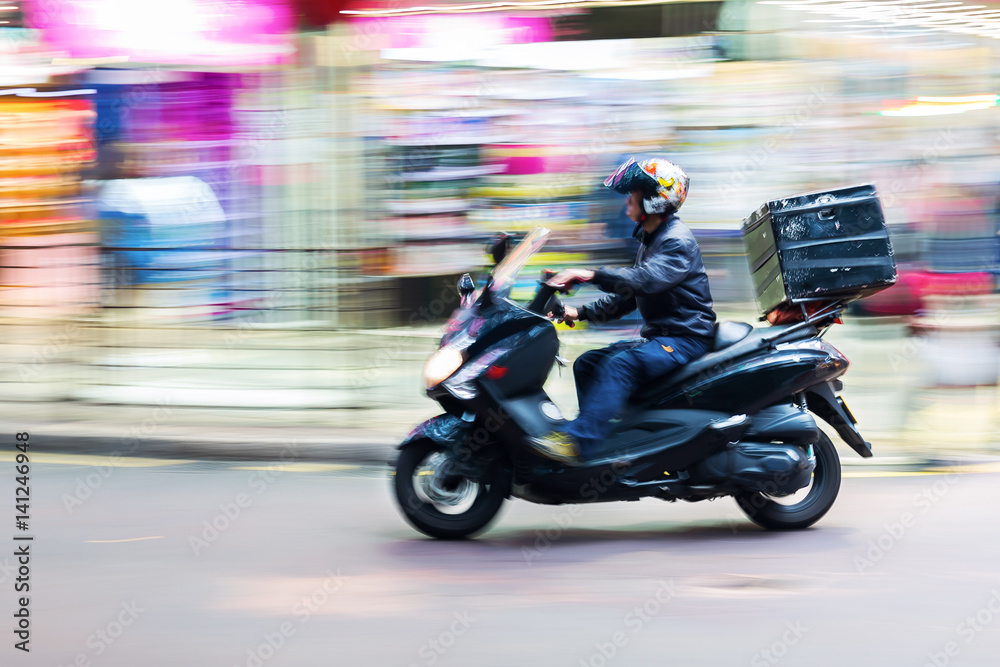 scooter messenger on the road in motion blur