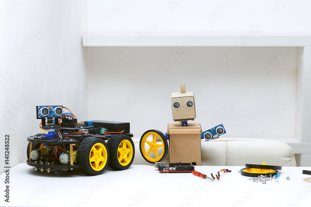 Obraz premium Two robots are on the table, around are parts for assembling the robot