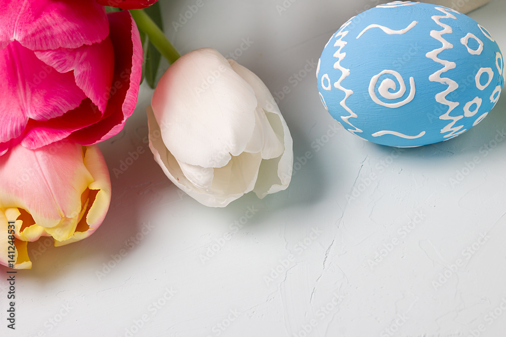 Painted easter eggs and bouquet of spring tulips closeup on a light blue background with space for congratulation Painted easter eggs and bouquet of spring tulips closeup on a light blue background with space for congratulation
