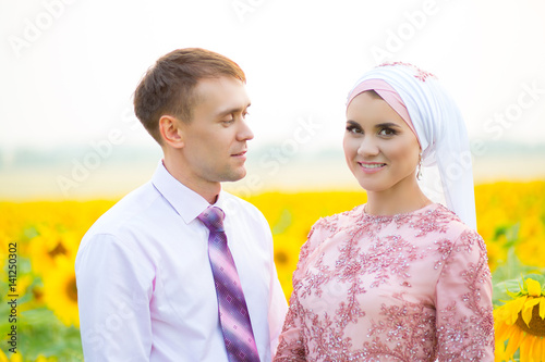 Sensual portrait of a young couple. Wedding islamic couple on sunflowers field. photo