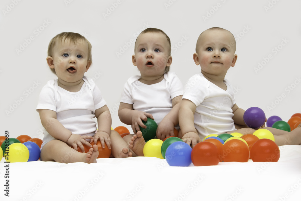 Baby triplets engaged and playing with colorful balls Baby triplets engaged and playing with colorful balls