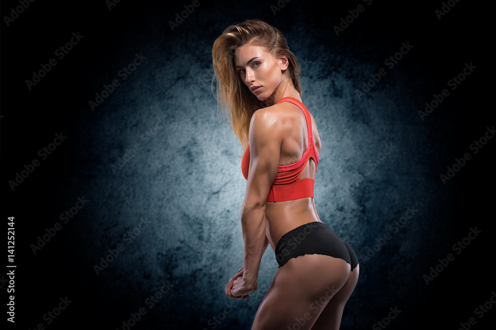 Muscular woman in studio on dark background