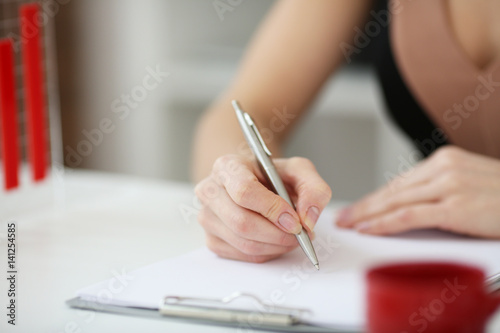 woman's hand with a pen writing on a sheet of paper on the background graphics. With depth of field image