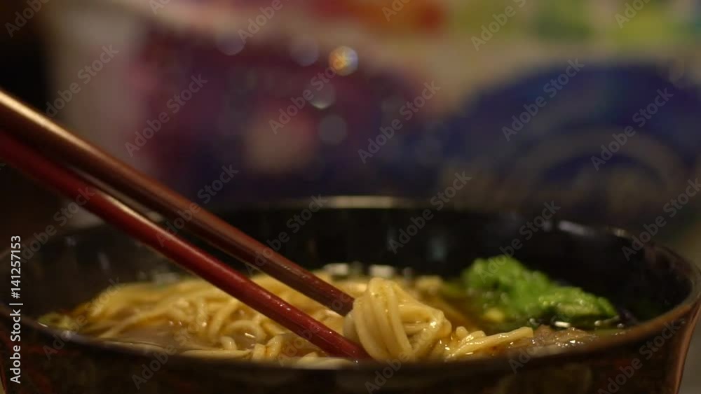 Slow motion people eating a bowl of beef noodles for dinner in an asian restaurant. Using sticks for eat the hot traditional chinese food in Taiwan.-Dan