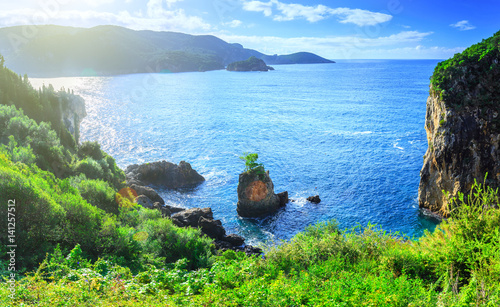 Beautiful summer panoramic seascape. View of the coastline into the sea bays with crystal clear azure water. Lonely rock with a tree on top. A small tree on top. Paleokastrica. Corfu. Greece. photo