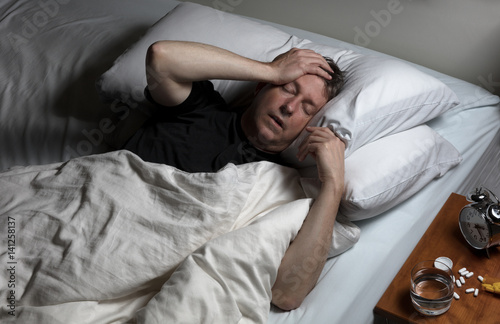 Mature man in physical pain while trying to fall asleep