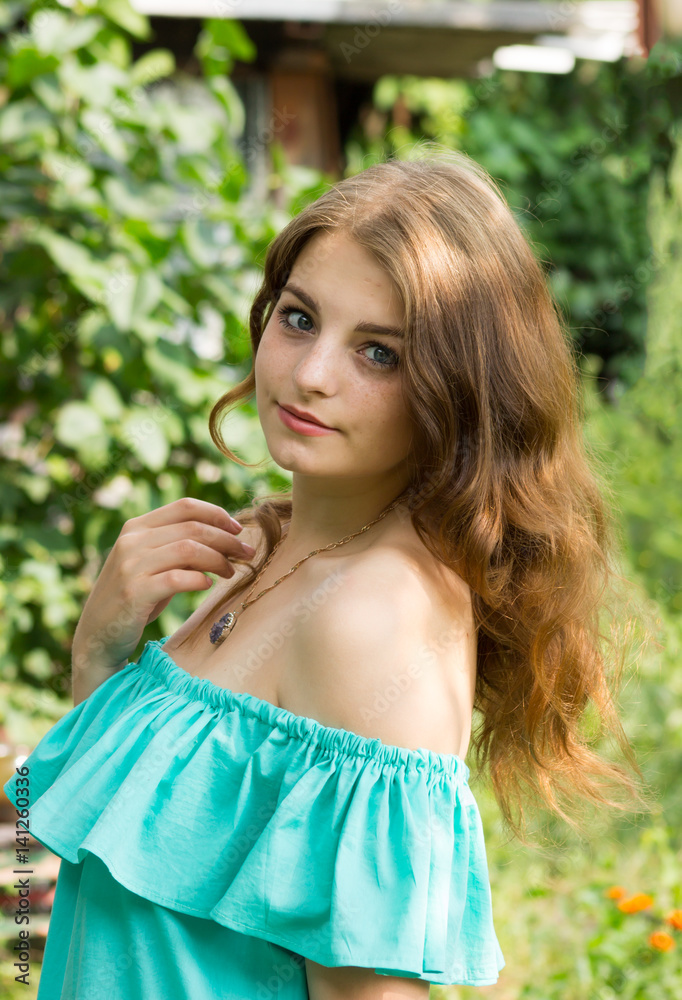 Naklejka premium beautiful girl posing in the garden . the height of spring. a green garden a beautiful green background . a tender portrait