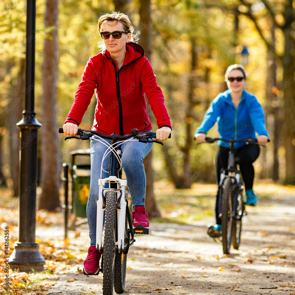 Fototapeta premium Two women riding bicycles in city 