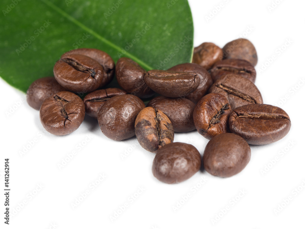 Naklejka premium Pile of coffee grains with green leaf over white isolated background.