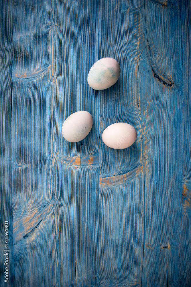 Easter eggs in soft colors on a blue shabby wooden table