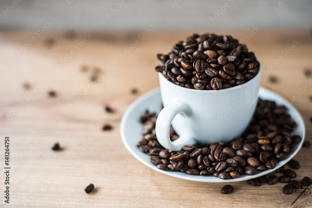 coffee cup filled by coffee beans on wooden background coffee cup filled by coffee beans on wooden background