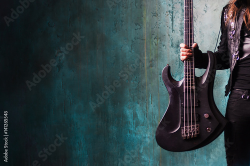 Man in black leather holding a guitar. Rocker and metalhead, youth style, music. Textured background, place for text © Ulia Koltyrina