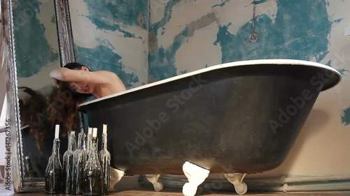 brunette woman have a bath at old fashion bathroom with candles in bottles photo