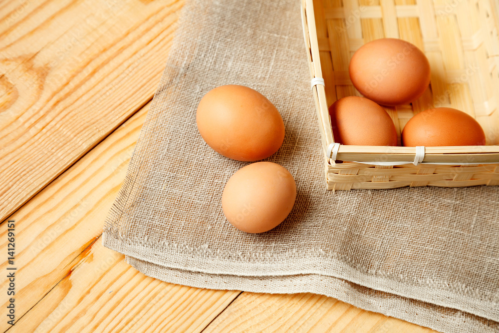 Raw eggs in wicker basket on wooden table Raw eggs in wicker basket on wooden table