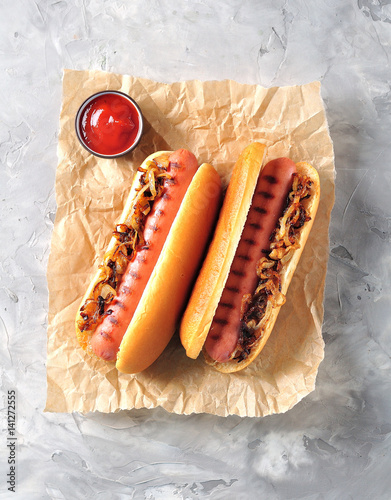 Two Hot dogs with crispy onion and ketchup.