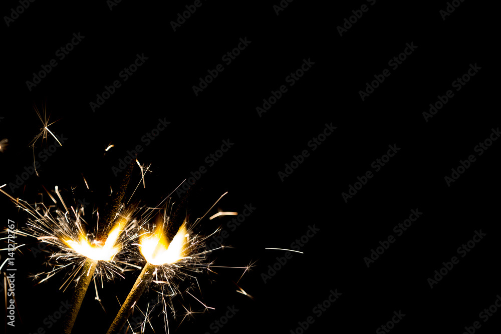 Three bright festive Christmas sparklers on black with free space