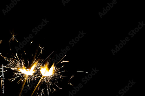 Three bright festive Christmas sparklers on black with free space