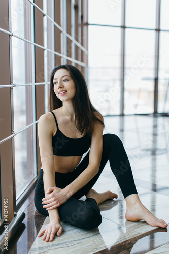 Portrait of the sports and beautiful girl in the gym at windows.