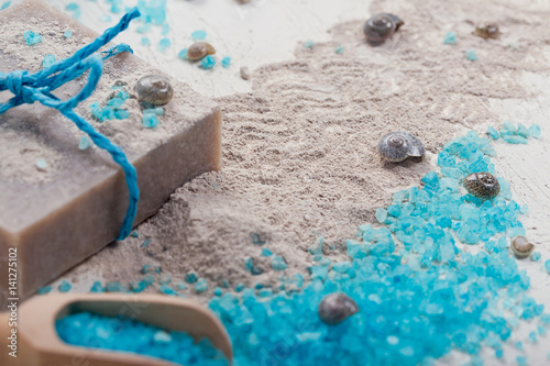 Cosmetic clay powder, homemade clay soap and blue sea salt on white background.