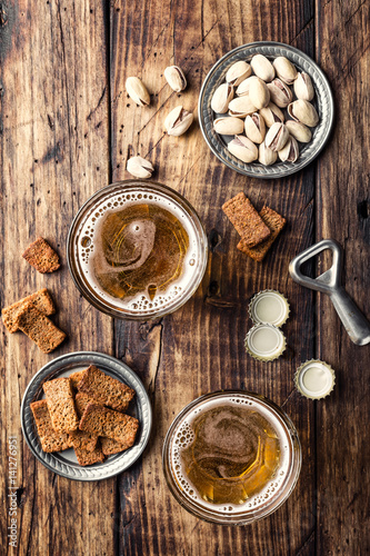 Two glasses of fresh beer and salty snacks on a brown wooden table, top view © Sunny Forest