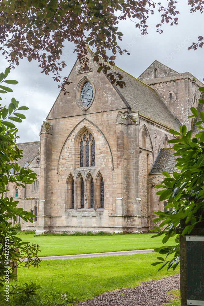 Pluscarden Abbey in Scotland with green grass and trees