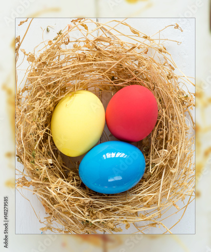 Happy Easter Card - space for text. Easter eggs in nest on rustic wooden background, selective focus image. 