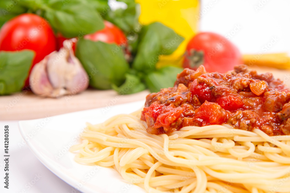 Spaghetti bolognese,some tomatoes, olive oil, basil, garlic, and raw pasta in the background Spaghetti bolognese,some tomatoes, olive oil, basil, garlic, and raw pasta in the background