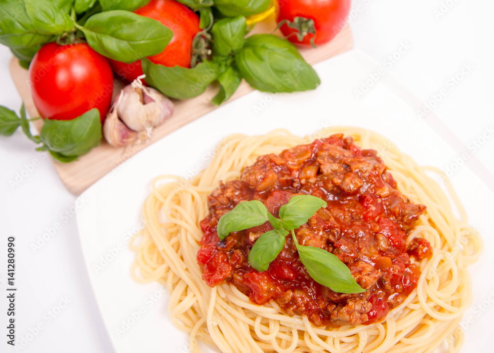 Spaghetti bolognese,some tomatoes, olive oil, basil, garlic, and raw pasta in the background Spaghetti bolognese,some tomatoes, olive oil, basil, garlic, and raw pasta in the background