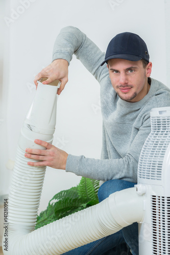 young technician installing air conditioning system indoors photo