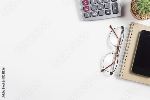 top view of working place elements on white table,Cactus,pen,,Mobile phone,Notebook,glasses,Paper, Paper Clips,with copy space.