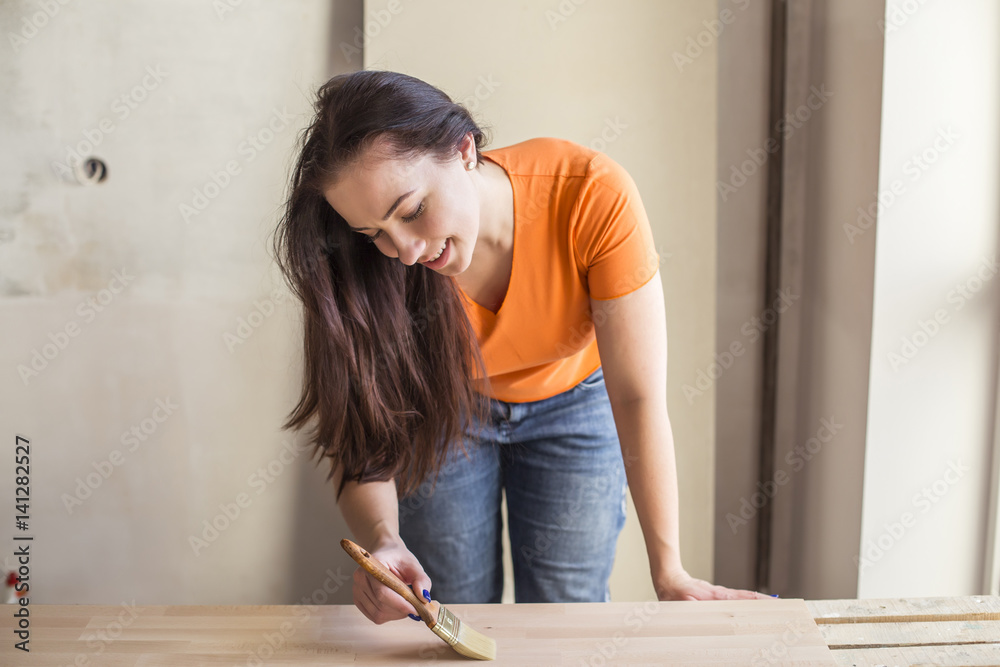 Handywoman painting wooden plank in workshop Handywoman painting wooden plank in workshop