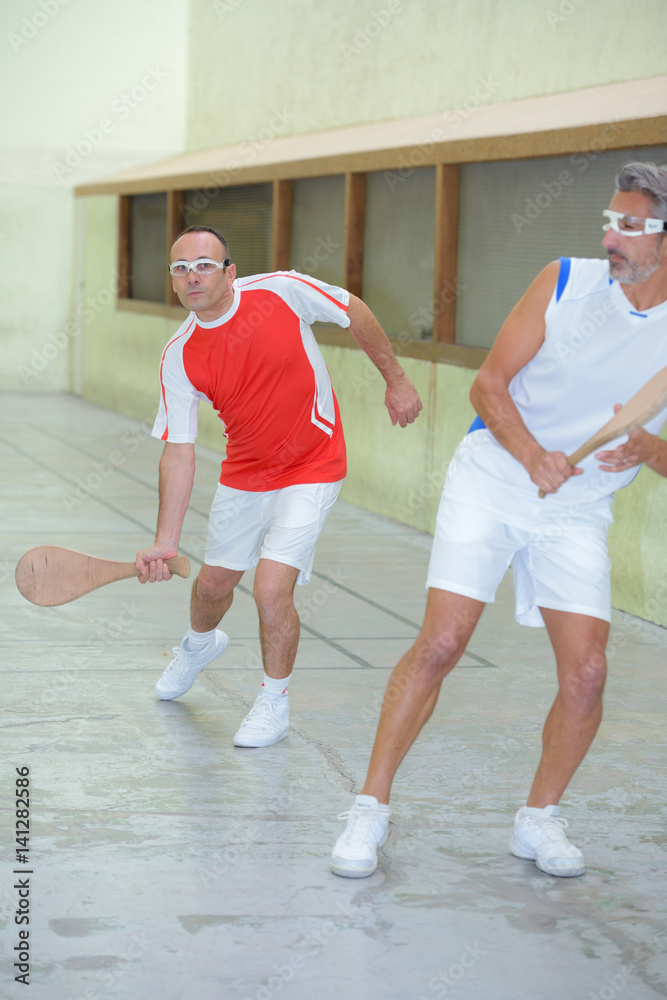 Men playing sport with wooden racket