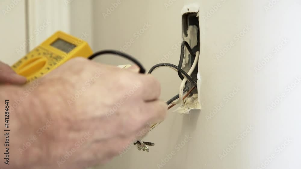 An electrician or homeowner handyman type checking the voltage of a ground fault outlet