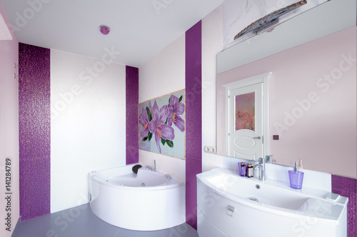 Modern Bathroom interior with a mosaic panel. White bathtub against violet and white wall