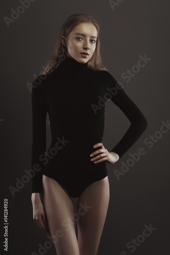 Model test with pretty woman in black body over a grey studio background