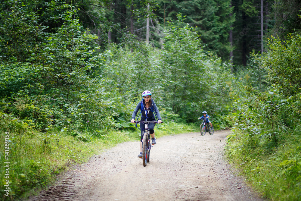 Young smiling woman Young woman riding bicycle in mountain forest on summer day Young smiling woman Young woman riding bicycle in mountain forest on summer day